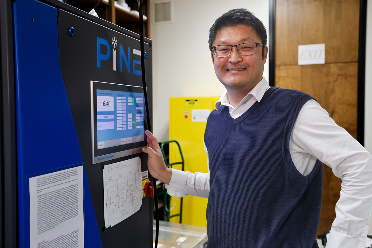 Naruki Hiranuma rests his hand next to the operating screen on the PINE chamber.