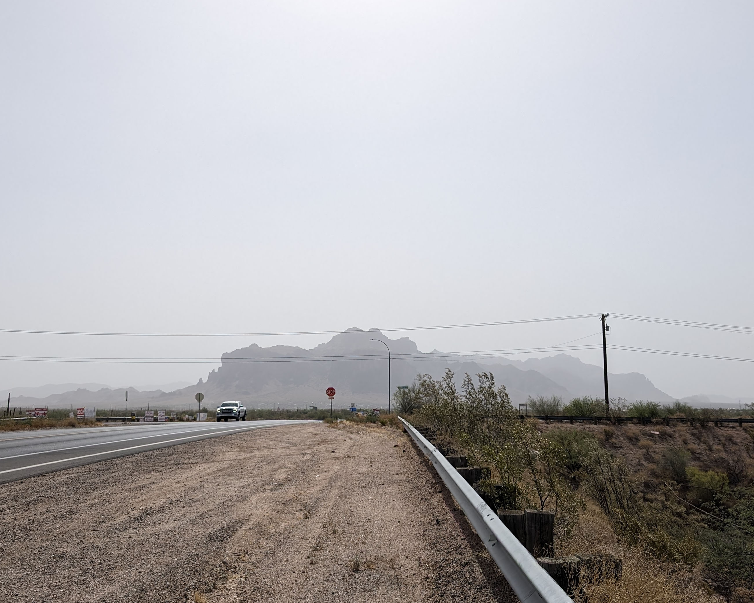 Taken along the side of a two-lane road, this photo shows dust obscuring desert mountains.