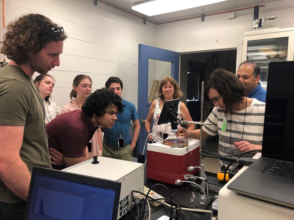 While classmates look on, a student bends down to see the experiment in which Emily Tansey is participating.